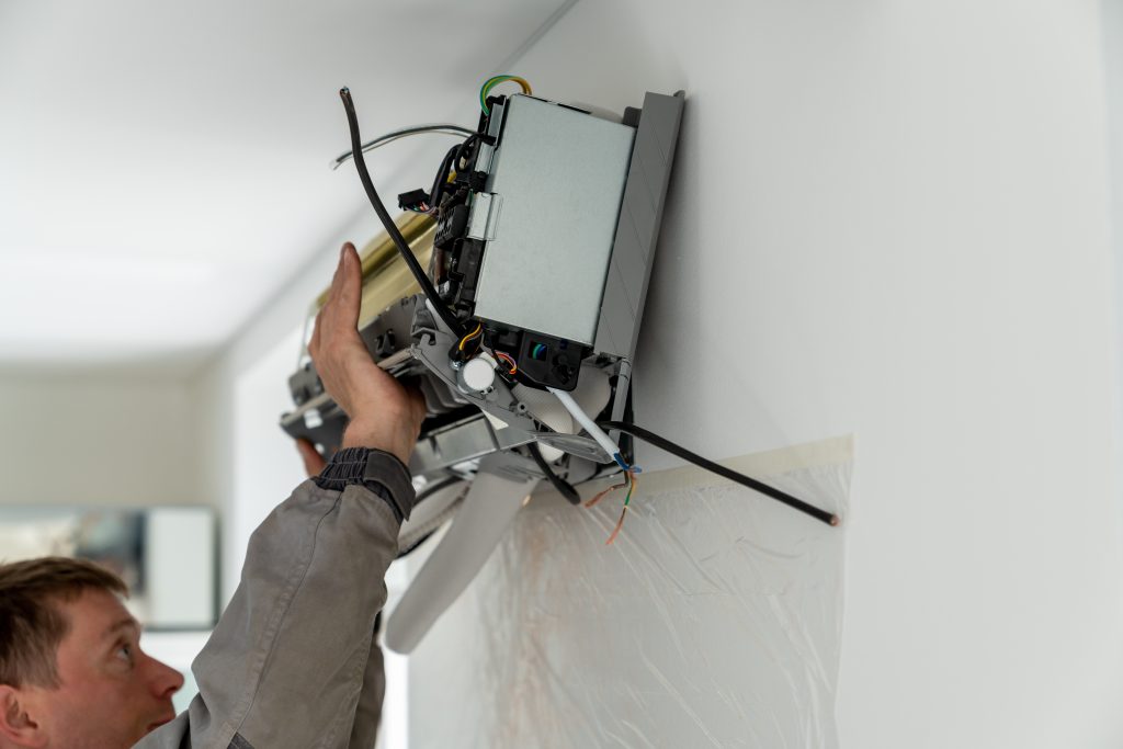 mini split maintenance Man technician worker in uniform fixing repairing apartment air conditioner, installing wall-mounted mini split. AC unit maintenance concept
